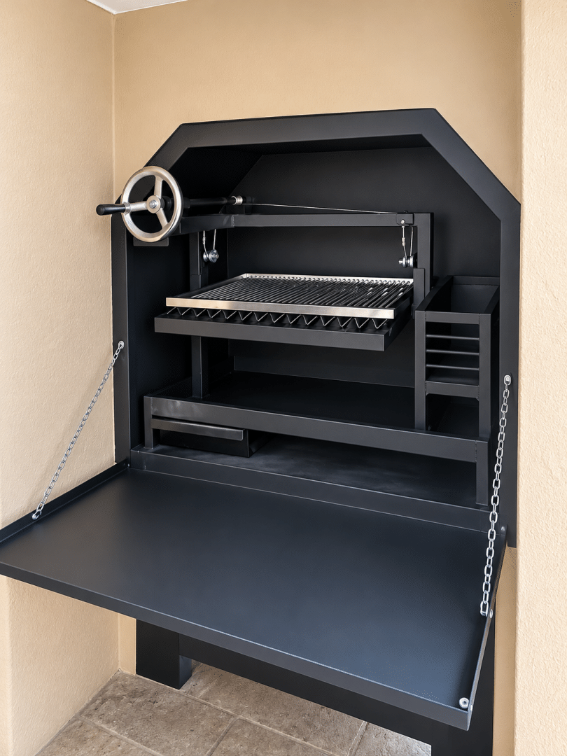 Black built-in Parrilla braai with adjustable stainless steel cooking grid, handwheel and fold-down front door